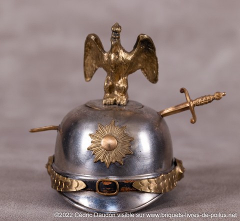 Rare exemplaire d’avant-guerre concrétisant symboliquement la victoire de la France en cas de conflit contre la Prusse (épée traversant le casque). Le casque est celui des gardes du corps de l’empereur.